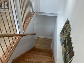 Toronto (Lambton Baby Point) apartment for rent - A staircase with a wooden handrail and steps leading to a landing with a white wall and a picture frame.