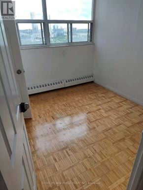Toronto (Agincourt South-Malvern West) condo for rent - A room with a wooden floor and a window overlooking a cityscape.