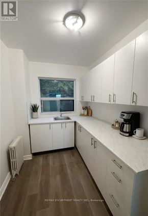 Hamilton (Durand) condo for rent - A kitchen with white cabinets and a window.
