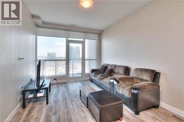 Kitchener condo for rent - A living room with a brown leather couch and a black ottoman.