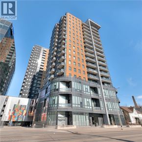 Kitchener condo for rent - A tall, modern building with a curved design and orange accents stands in the foreground.
