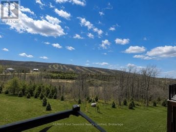 Blue Mountains condo for rent - A view from a balcony overlooking a green landscape with trees and a mountain in the distance.