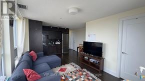 Toronto (Willowdale East) condo for rent - A living room with a blue couch and a television on a wooden stand.