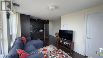Toronto (Willowdale East) condo for rent - A living room with a blue couch and a television on a wooden stand.