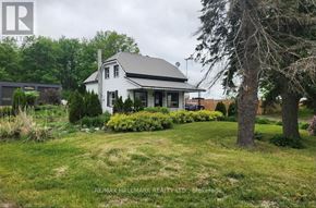 Springwater (Elmvale) apartment for rent - A white house with a black roof is surrounded by greenery.