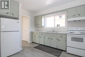 Peterborough (Town Ward 3) triplex for rent - A white refrigerator is in a kitchen with white cabinets and a sink.