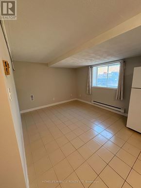 Richmond Hill triplex for rent - A spacious room with a window and a tiled floor.