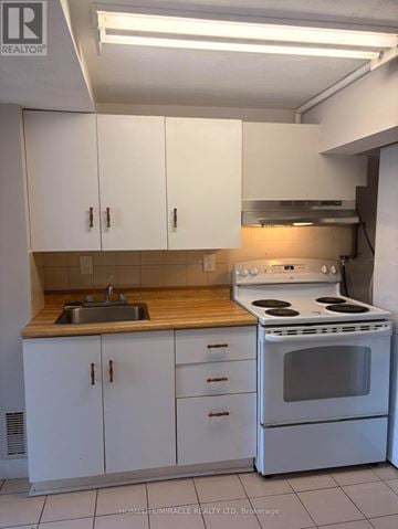 Richmond Hill triplex for rent - A kitchen with white cabinets and a stove top oven.
