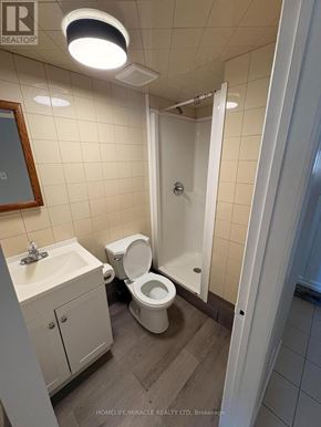 Richmond Hill triplex for rent - A bathroom with a toilet, sink, and mirror.