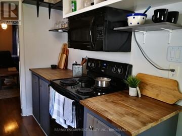 Hamilton (Eastmount) apartment for rent - A kitchen with a wooden counter top and a black stove.