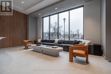 Burlington (Brant) condo for rent - A modern living room with a large window and a view of a street with lamp posts.