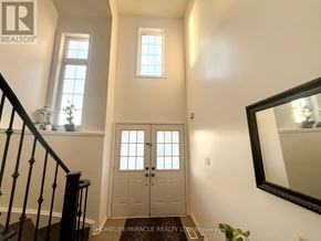 Brantford apartment for rent - A hallway with a wooden door, a mirror, and a potted plant.