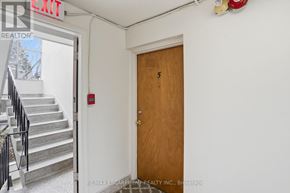 Hamilton (Strathcona) multi-family for rent - A wooden door with the number 5 on it is in a white room.