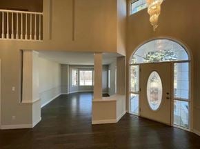 Winnipeg apartment for rent - A large, empty room with a chandelier and a view of trees through a window.