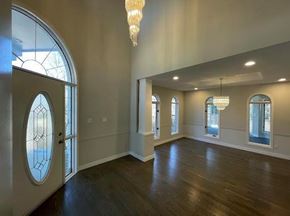 Winnipeg apartment for rent - A spacious room with wooden floors and a large arched window.