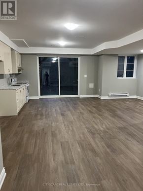 Pickering apartment for rent - A spacious room with wooden flooring and a kitchen area.