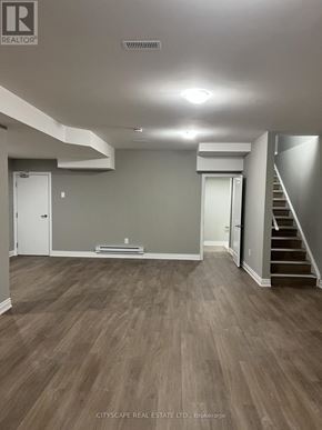 Pickering apartment for rent - A spacious room with wood flooring and a staircase on the right side.