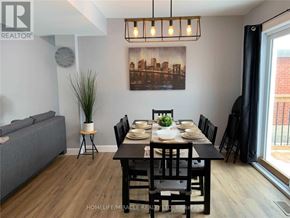 Niagara Falls (Hospital) apartment for rent - A dining room with a grey couch, a wooden table set for six, and a cityscape picture on the wall.