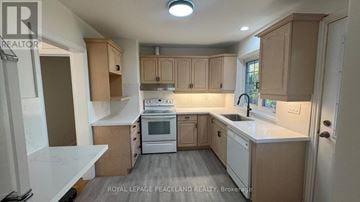 Toronto (Banbury-Don Mills) apartment for rent - A kitchen with white appliances and wooden cabinets.