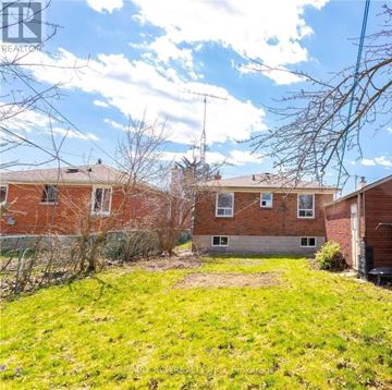 Toronto (Eglinton East) apartment for rent - A grassy area in front of a brick building with a sign that says REALTOR.