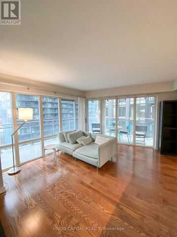 Toronto (Moss Park) condo for rent - A living room with a white couch and wooden floors.