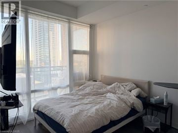 Kitchener condo for rent - A bedroom with a large bed and a television.