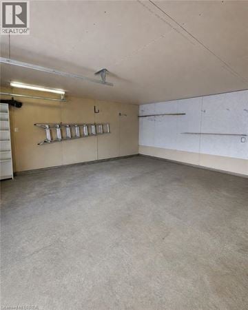 Brantford apartment for rent - A spacious room with a concrete floor and walls, and a row of shelves on the left wall.