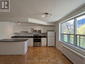 Toronto (Rosedale-Moore Park) condo for rent - A well-lit kitchen with wooden flooring and white cabinets.