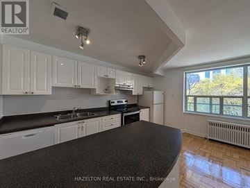 Toronto (Rosedale-Moore Park) condo for rent - A kitchen with white cabinets and a black countertop.