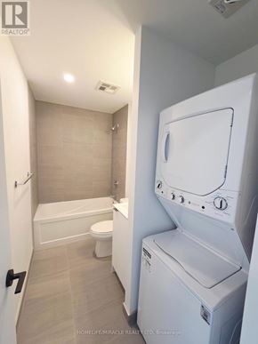 Toronto (Clairlea-Birchmount) condo for rent - A white washing machine is in a bathroom with a tub, toilet and sink.