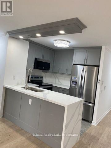 Mississauga (Hurontario) condo for rent - A modern kitchen with a stainless steel refrigerator and a flat screen TV mounted above the sink.