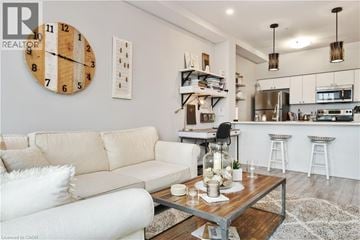 Hamilton condo for rent - A living room with a white couch and a wooden clock on the wall.