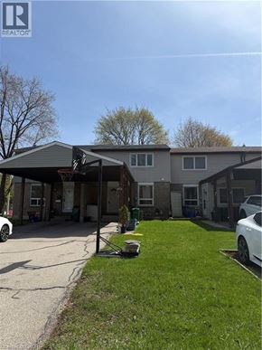 Hamilton condo for rent - A realtor photo of a house with a carport and a white car parked in front.