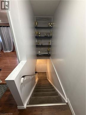 Hamilton condo for rent - A staircase with a white railing and wooden steps leading to a landing with shelves.