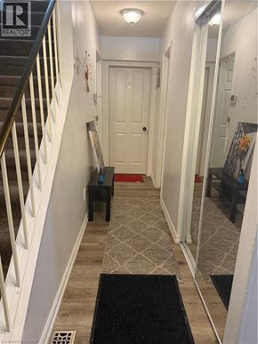 Hamilton condo for rent - A hallway with a black doormat and a white door.