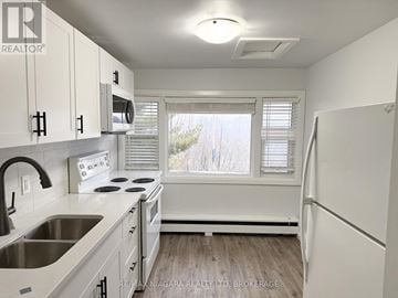 Niagara Falls (Downtown) multi-family for rent - A kitchen with white cabinets and a window with blinds.