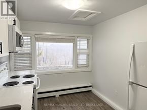 Niagara Falls (Downtown) multi-family for rent - A white stove in a small kitchen with a window.