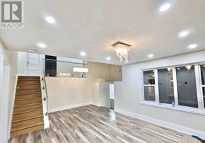 Kitchener apartment for rent - A spacious room with wooden flooring and a chandelier.