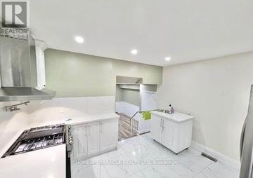 Kitchener apartment for rent - A white kitchen with a refrigerator, cabinets, and a stove top oven.