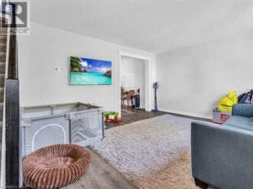 London apartment for rent - A living room with a grey couch, a white rug, and a painting of a beach scene on the wall.