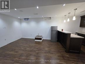 Milton (Sc Scott) apartment for rent - A spacious room with wooden flooring and a kitchen area with a refrigerator and countertop.