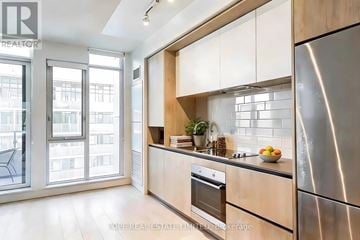 Toronto (Regent Park) condo for rent - A modern kitchen with wooden cabinets and stainless steel appliances.