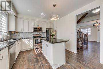Oakville (Go Glenorchy) townhouse for rent - A modern kitchen with white cabinets and a wooden floor.