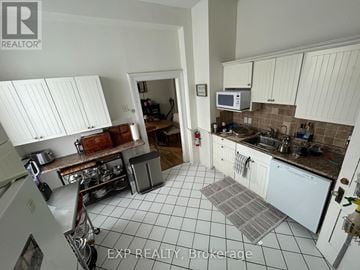 London East (East F) fourplex for rent - A kitchen with white cabinets and a tiled floor.