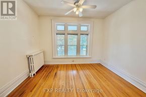 London East (East F) fourplex for rent - A bedroom with a bed, a window, and a coat rack.