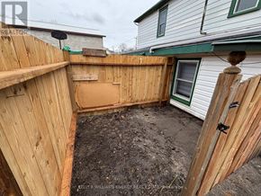 Prince Edward County (Picton Ward) duplex for rent - A backyard with a wooden fence and a dirt ground.
