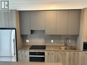 Markham (Unionville) condo for rent - A kitchen with a refrigerator on the left and a sink with a faucet on the right.