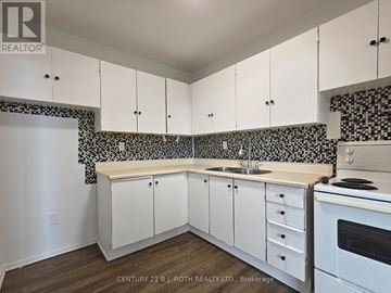 Barrie (Allandale) apartment for rent - A kitchen with white cabinets and a black and white tiled backsplash.