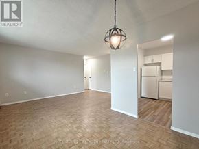 Barrie (Allandale) apartment for rent - A well-lit, empty room with a wooden floor and a pendant light hanging from the ceiling.
