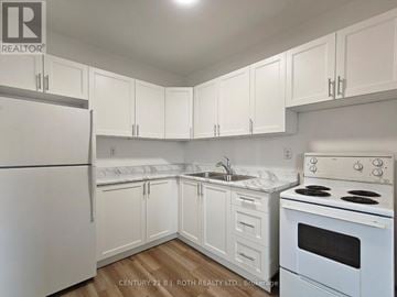 Barrie (Allandale) apartment for rent - A kitchen with white appliances and cabinets.